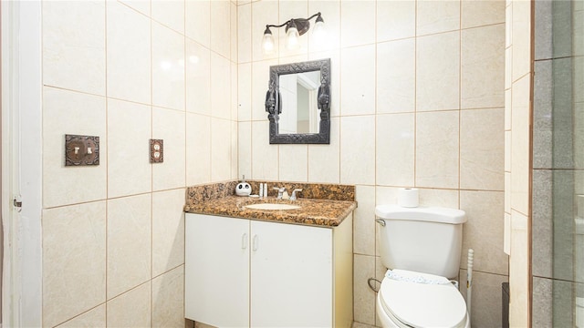 bathroom with tile walls, vanity, and toilet