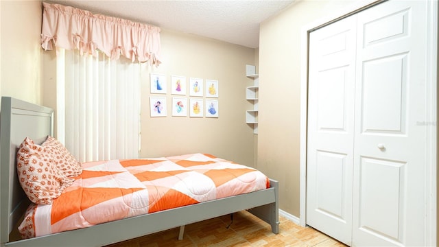 bedroom with a closet, a textured ceiling, and light wood-type flooring