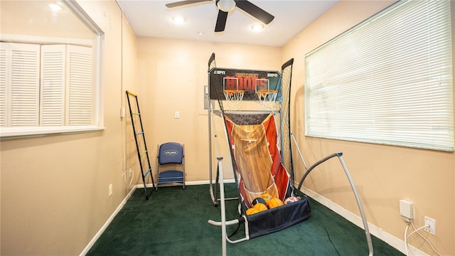 exercise room featuring dark colored carpet, a textured ceiling, and ceiling fan