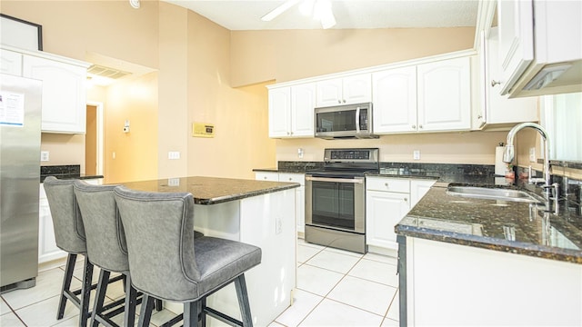 kitchen with appliances with stainless steel finishes, sink, a center island, lofted ceiling, and white cabinets