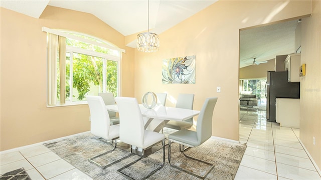 tiled dining space with ceiling fan with notable chandelier and vaulted ceiling