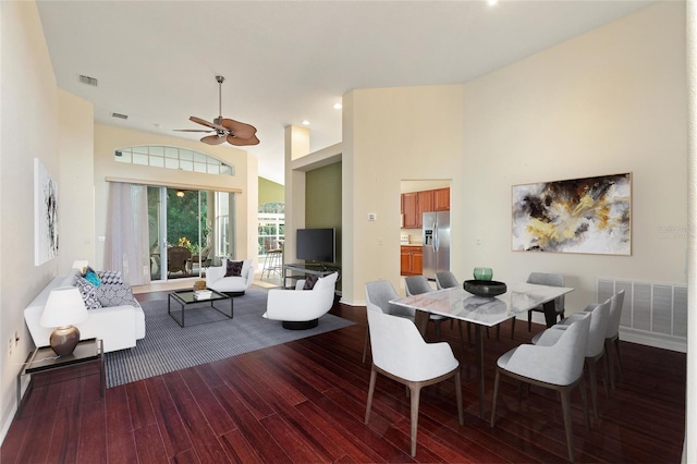 dining space with a high ceiling, wood-type flooring, and ceiling fan