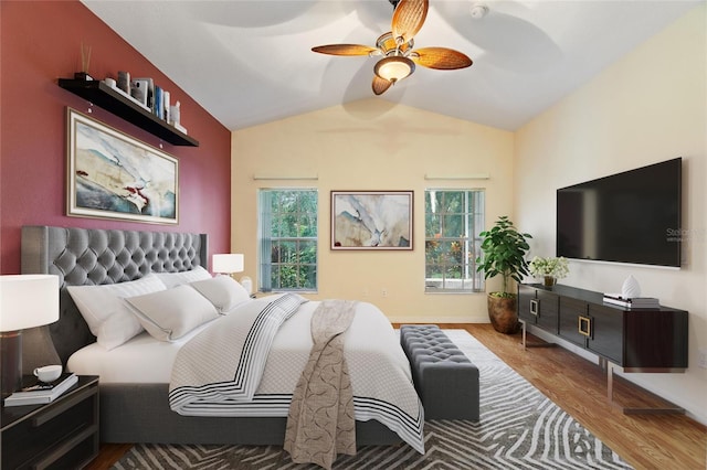 bedroom featuring vaulted ceiling, hardwood / wood-style flooring, multiple windows, and ceiling fan