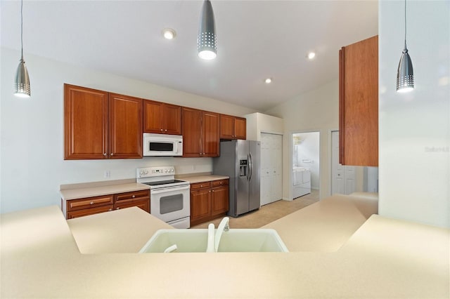 kitchen featuring white appliances, sink, independent washer and dryer, hanging light fixtures, and lofted ceiling