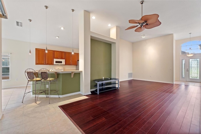 living room featuring a high ceiling, light hardwood / wood-style flooring, and ceiling fan