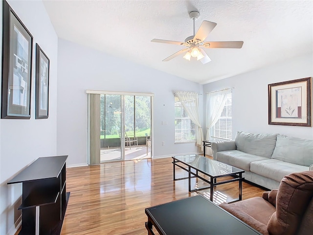 living room featuring light hardwood / wood-style floors, a textured ceiling, vaulted ceiling, and ceiling fan