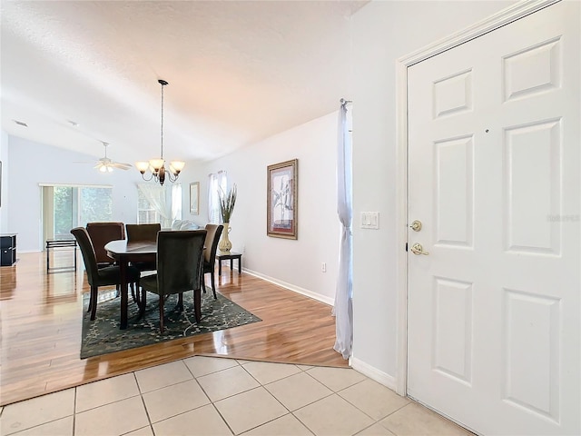 dining space with lofted ceiling, light wood-type flooring, and ceiling fan with notable chandelier