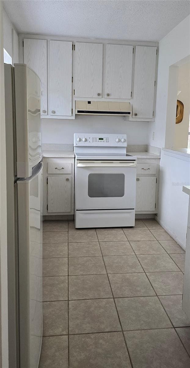 kitchen featuring white cabinetry, a textured ceiling, light tile patterned floors, and white appliances