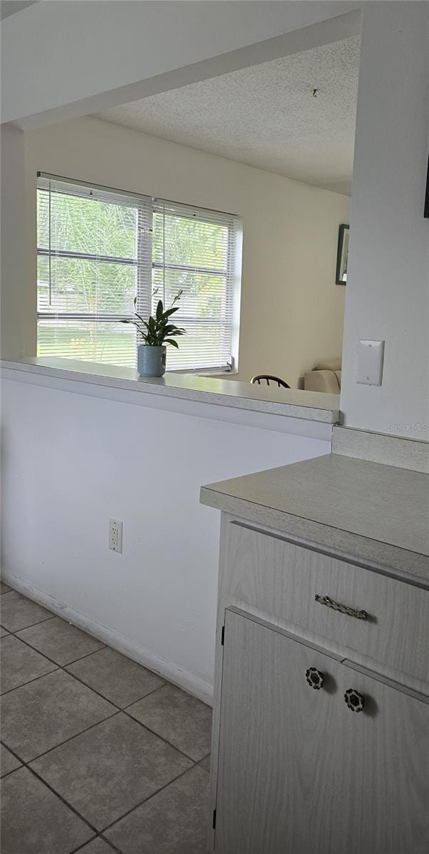 laundry room featuring a textured ceiling, tile patterned floors, and plenty of natural light