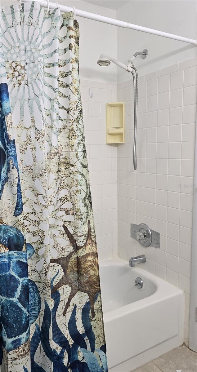 bathroom featuring shower / bath combo with shower curtain and tile patterned flooring