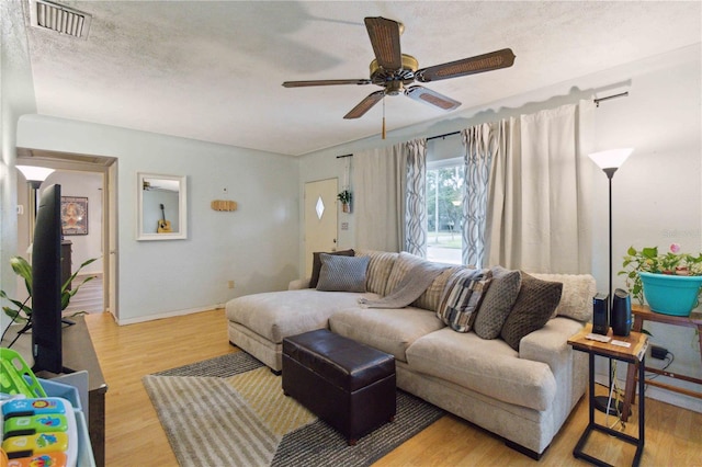 living room with hardwood / wood-style floors, a textured ceiling, and ceiling fan