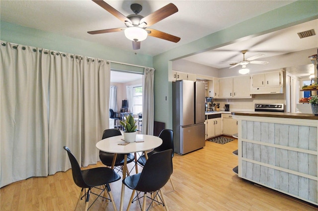 dining area with light wood-type flooring and ceiling fan