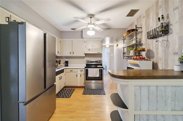 kitchen featuring tasteful backsplash, appliances with stainless steel finishes, cream cabinets, light hardwood / wood-style floors, and ceiling fan