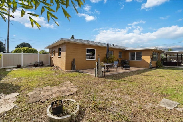 rear view of property with fence, a lawn, and a patio area