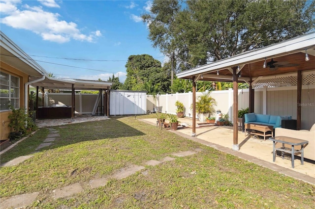 view of yard featuring a fenced backyard, outdoor lounge area, a ceiling fan, a shed, and a patio