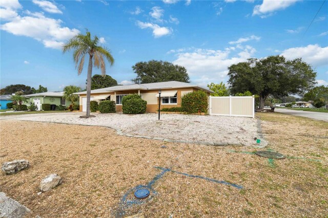 ranch-style house featuring stucco siding and fence