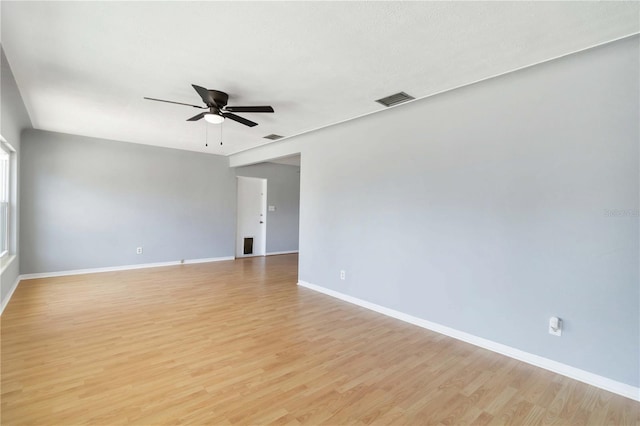 spare room featuring baseboards, a ceiling fan, visible vents, and light wood-style flooring