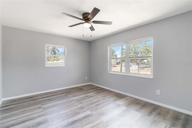 empty room featuring baseboards, wood finished floors, and ceiling fan
