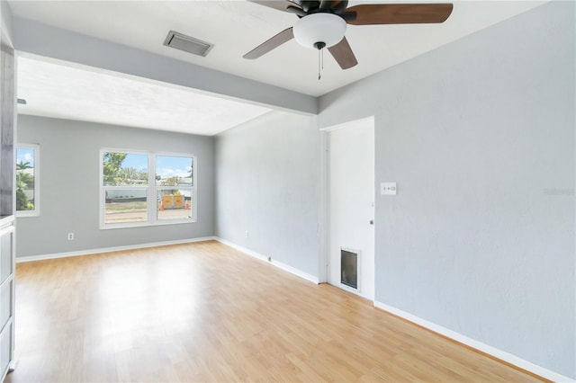 spare room featuring visible vents, beamed ceiling, light wood-type flooring, baseboards, and ceiling fan