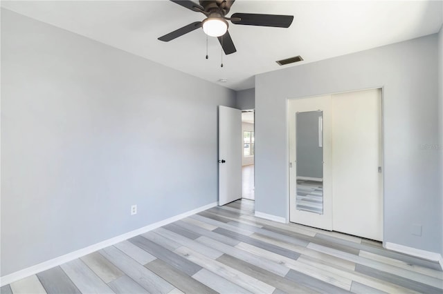 unfurnished bedroom featuring baseboards, light wood-style flooring, visible vents, and a ceiling fan
