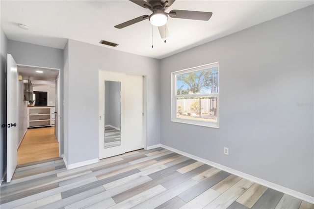unfurnished bedroom with baseboards, visible vents, ceiling fan, and light wood finished floors
