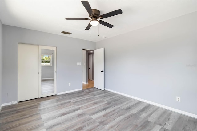 unfurnished bedroom featuring a ceiling fan, visible vents, wood finished floors, and baseboards