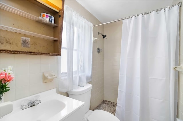full bathroom featuring a healthy amount of sunlight, toilet, tiled shower, and a sink