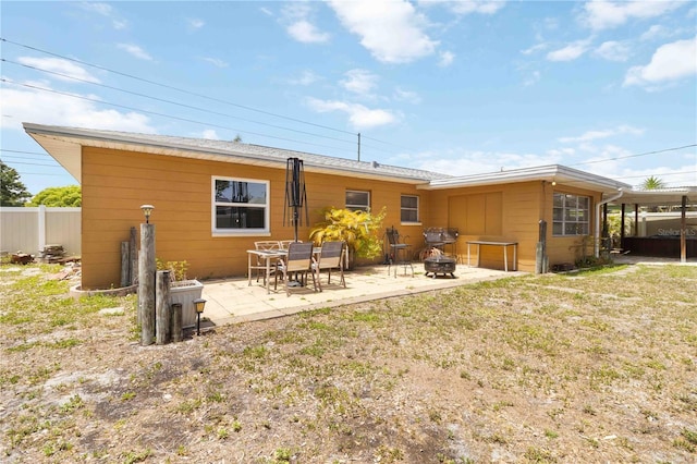 rear view of house featuring an outdoor fire pit, fence, and a patio area