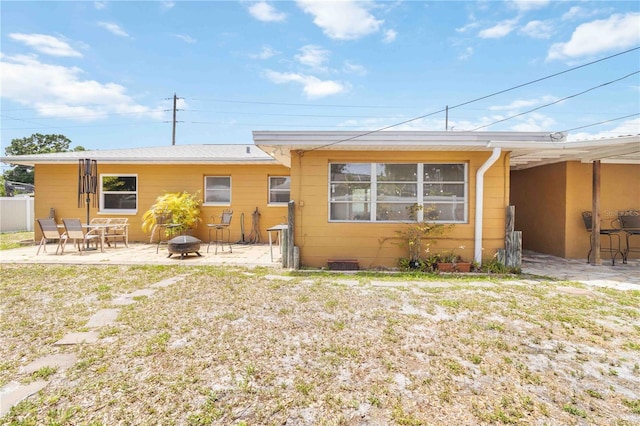 back of property featuring a fire pit, a patio, and fence