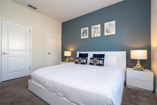 bedroom featuring dark colored carpet and a textured ceiling