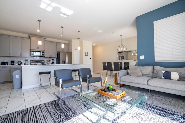 living room featuring visible vents, marble finish floor, and an inviting chandelier