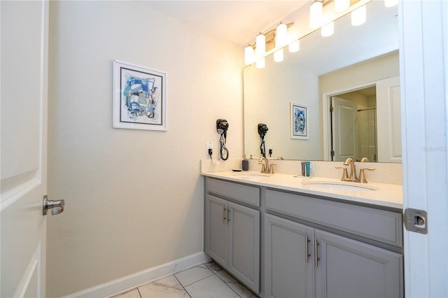 full bath featuring baseboards, a sink, marble finish floor, and double vanity
