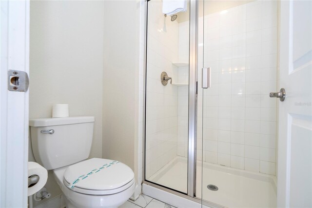 bathroom with a shower with shower door and toilet