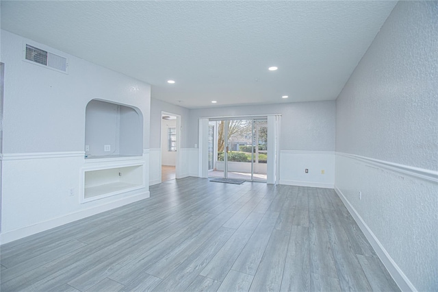 unfurnished living room featuring hardwood / wood-style floors and a textured ceiling