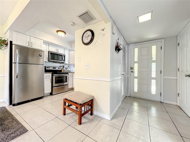 kitchen featuring stainless steel appliances, light tile patterned floors, and white cabinets