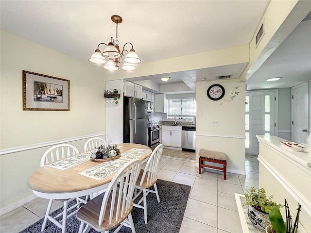 dining area with sink, a chandelier, and light tile patterned flooring