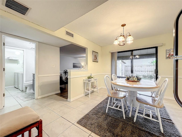 dining area featuring light tile patterned floors, a textured ceiling, an inviting chandelier, and separate washer and dryer