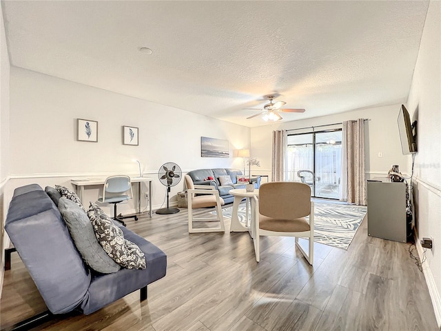 living room with hardwood / wood-style floors, a textured ceiling, and ceiling fan