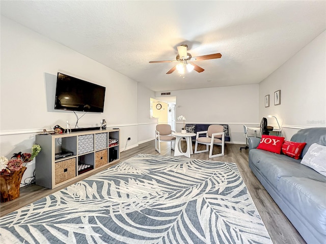 living room with a textured ceiling, hardwood / wood-style flooring, and ceiling fan