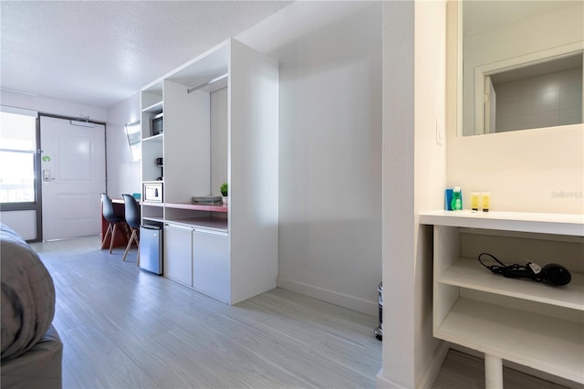 kitchen featuring light hardwood / wood-style floors, a textured ceiling, and built in desk