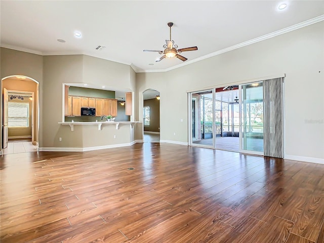 unfurnished living room with ceiling fan, sink, wood-type flooring, and ornamental molding