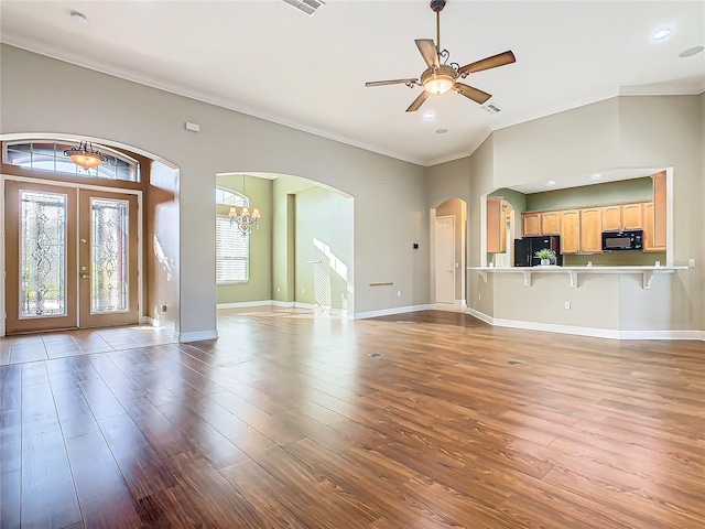 unfurnished living room with ceiling fan with notable chandelier, wood-type flooring, ornamental molding, and french doors