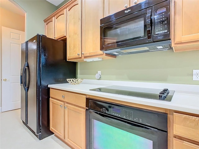 kitchen with light brown cabinets, light tile patterned floors, and black appliances