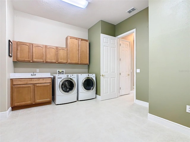 clothes washing area featuring washer and dryer and cabinets