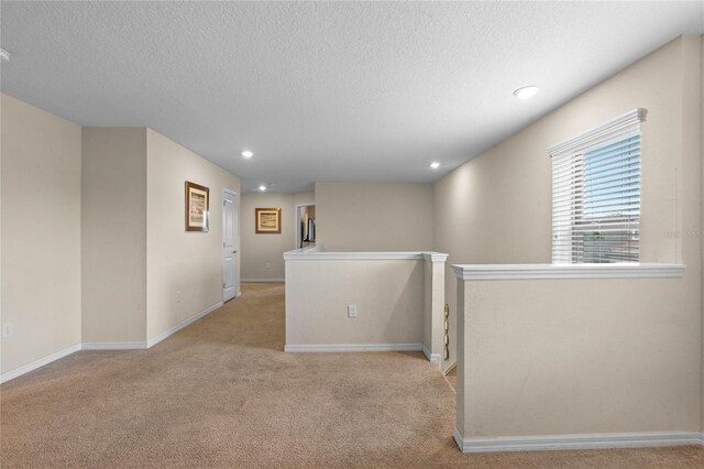 hall with light carpet and a textured ceiling