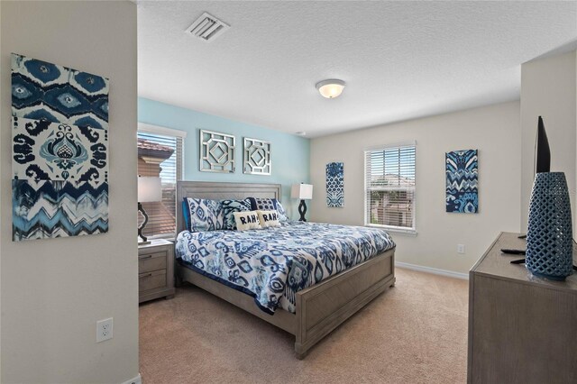 bedroom with a textured ceiling and light colored carpet