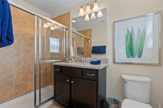 bathroom featuring a shower with door, vanity, and toilet