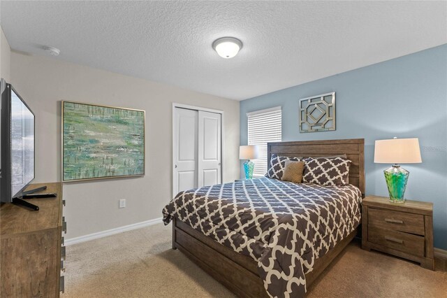 bedroom featuring a textured ceiling, light colored carpet, and a closet