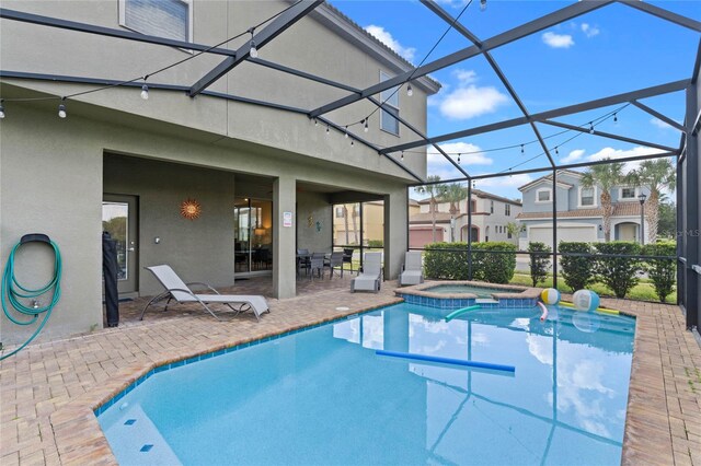 view of swimming pool with an in ground hot tub, a patio area, and glass enclosure