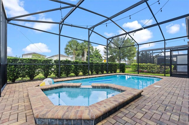 view of swimming pool featuring a patio, a lanai, and an in ground hot tub